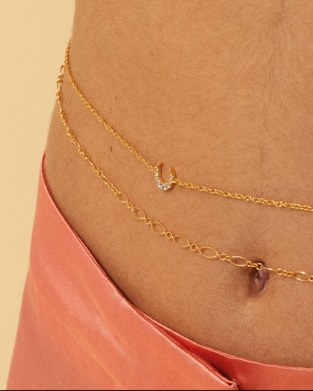 APSARA - Chaîne de taille DIA portée, gros plan. Bijou de corps minimaliste en anneaux ovales dorés. Fabrication française.