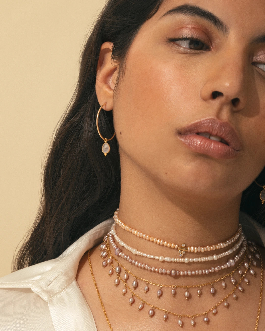 Superposition de colliers nacrés APSARA, mettant en scène le collier DALHIA rose et le collier Pearl portés par une femme.