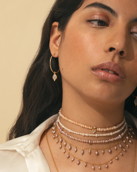 Superposition de colliers nacrés APSARA, mettant en scène le collier DALHIA rose et le collier Pearl portés par une femme.