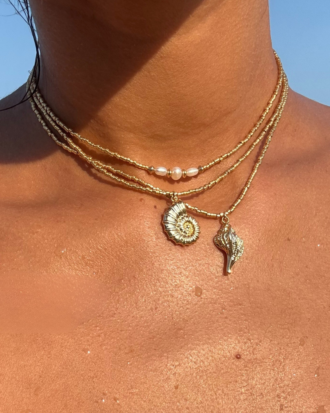 APSARA - Collier ras de cou BORA-BORA porté en accumulation avec le collier URSULA. Bijoux en fines perles dorées et pendentifs coquillage, faits main en France