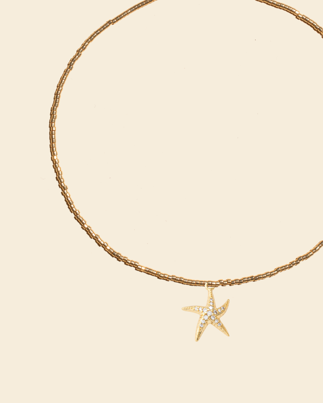 APSARA - Collier ras-de-cou STELLA en perles dorées avec pendentif Étoile de merOr et cristaux zircons brillants . Fait main en France.