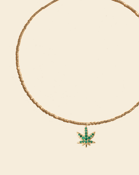 APSARA - Collier ras-de-cou HIGH en perles dorées avec pendentif feuille dorée et cristaux zircons verts emeraude.