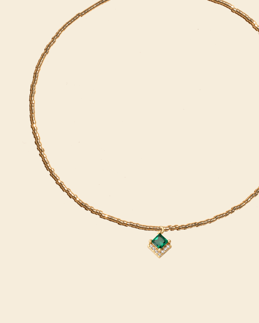 APSARA - Collier ras de cou OASIS en fines perles dorées et pendentif Zircon Emeraude. Bijou fait main en France.