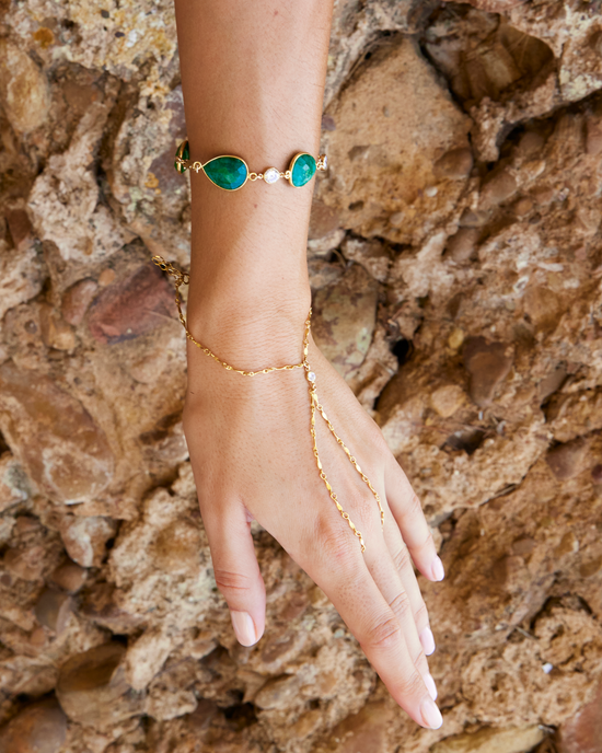 Bracelet Karma porté au poignet sur un fond de roche. Bijou idéal pour l'été.