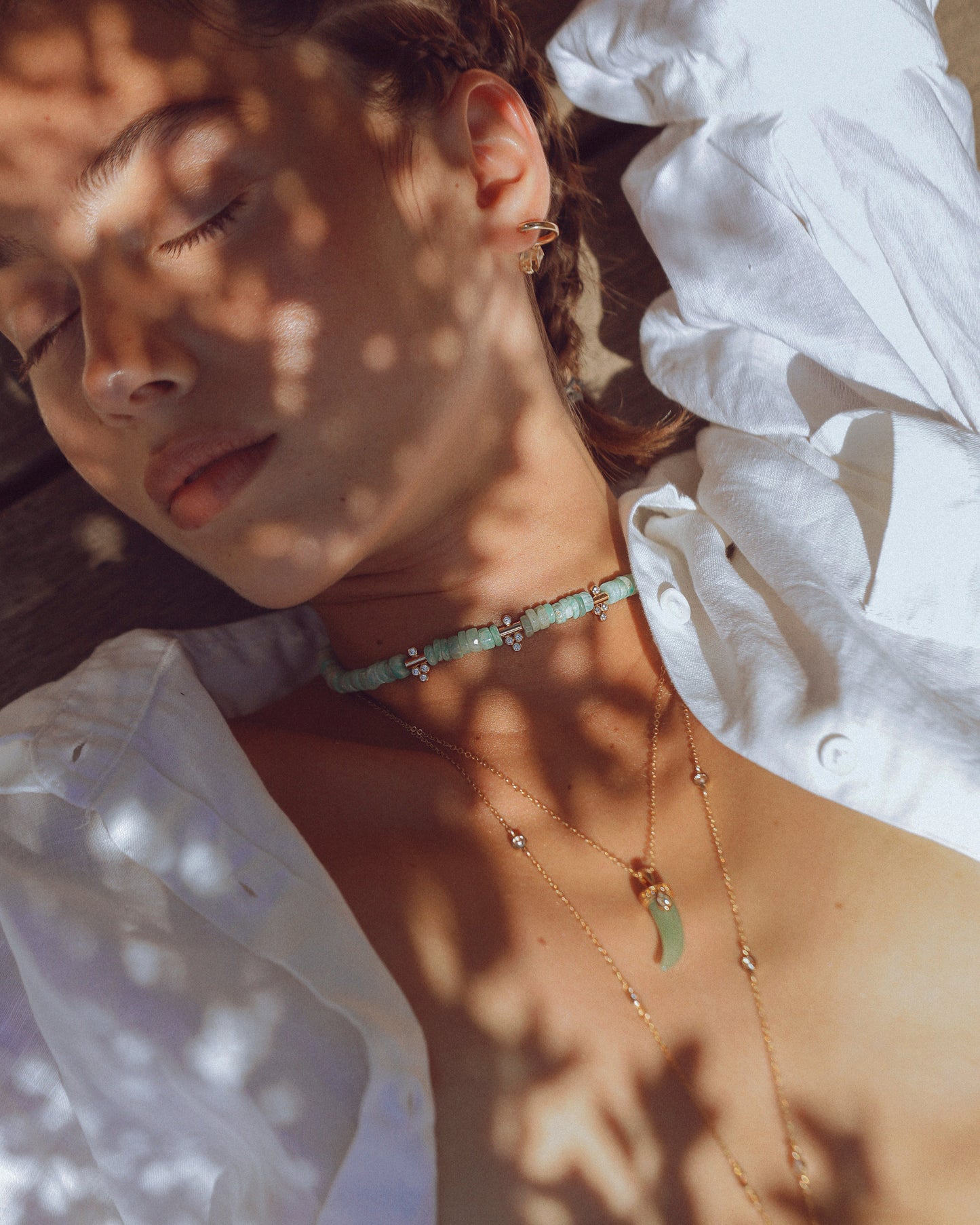 Femme faisant la sieste à l'ombre d'un olivier, portant le collier Moana APSARA en amazonite avec son pendentif zirconium scintillant.