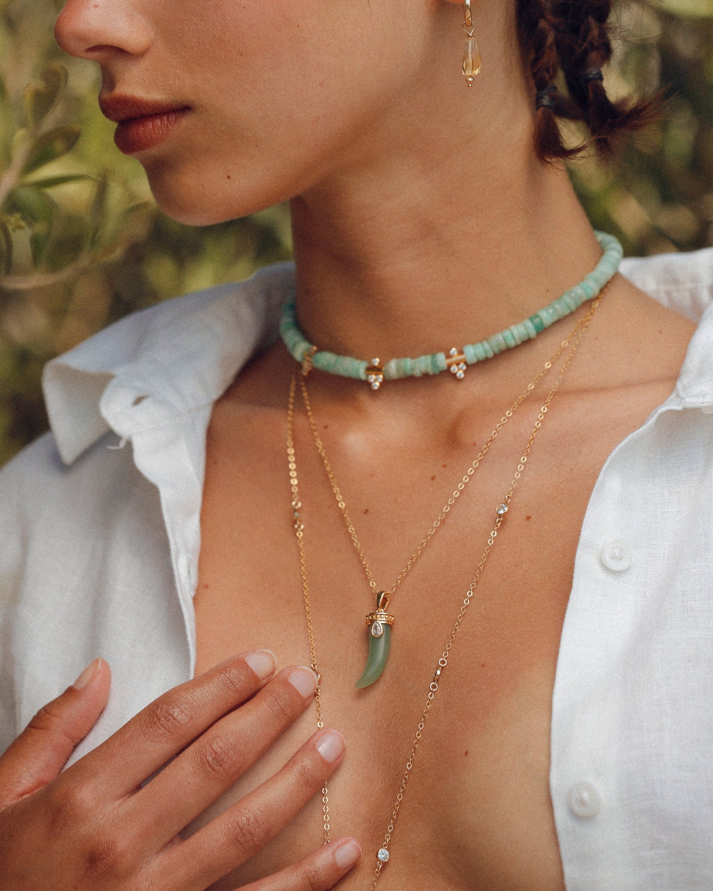 Femme portant une accumulation de colliers APSARA dorés, incluant le Moana en amazonite, associée à une chaîne de corps sensuelle.