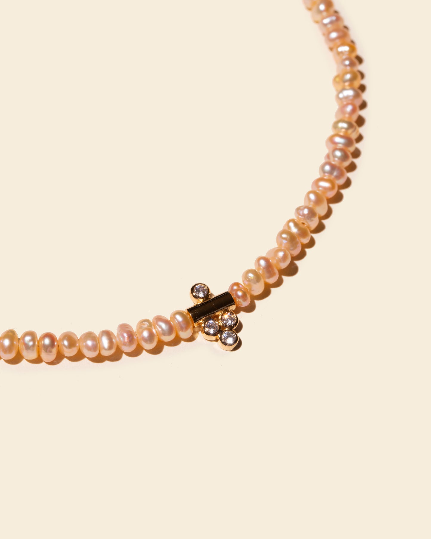Gros plan sur le pendentif plaqué or du collier DALHIA par APSARA, serti de 4 oxydes de zirconium scintillants.